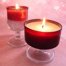 Load image into Gallery viewer, Two lit candles in red holders on a pink background with heart shapes.